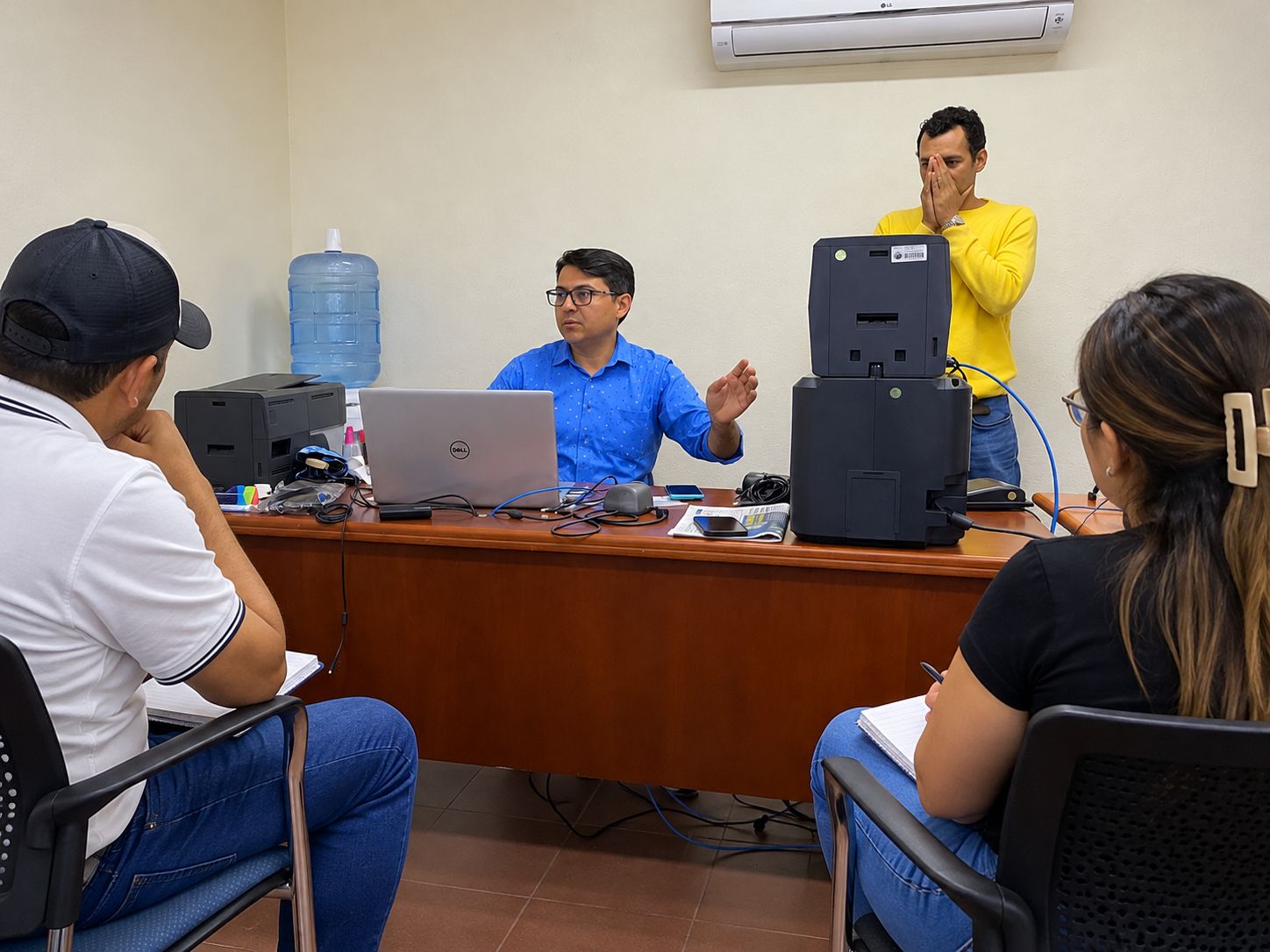 Engineer training staff on how to use ID card printers connected to a laptop